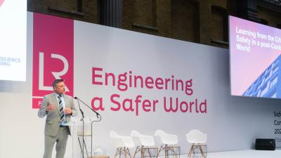 A photo of a speaker on stage at the Safer World Conference.